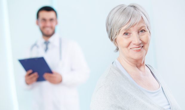 Senior patient looking at camera with doctor on background...