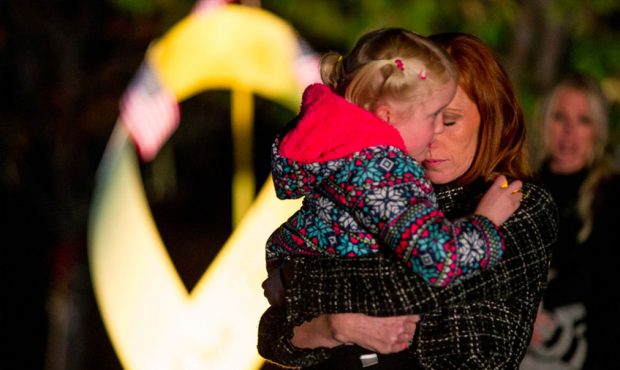 Jennie Taylor holds her daughter while speaking to those gathered for a vigil honoring her late hus...