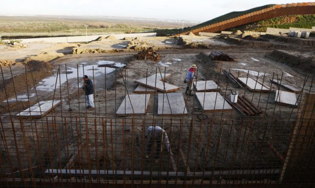 Men work on a condominium project in Tijuana, with the U.S.-Mexico border barrier in the background...