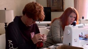 Logan Merrill sits next to his mother Tori Merrill as she sews "Just Don't" bags.