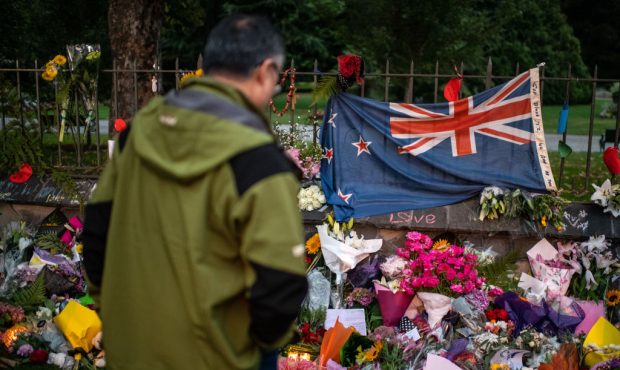CHRISTCHURCH, NEW ZEALAND - MARCH 17: A man pauses next to a New Zealand flag hung amongst flowers ...