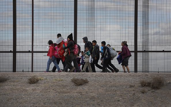 Central American immigrants walk along the border fence after crossing the Rio Grande from Mexico o...