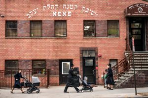 Pedestrians walk past the Yeshiva Kehilath Yakov School in the South Williamsburg neighborhood, April 9, 2019 in the Brooklyn borough of New York City. New York City has ordered all yeshivas in a heavily Orthodox Jewish section of Brooklyn to exclude from classes all students who aren't vaccinated against measles or face fines or possible closure. The order comes amid a recent outbreak of over 285 measles cases in Brooklyn and Queens, most of which have been concentrated in the Orthodox Jewish communities. (Photo by Drew Angerer/Getty Images)