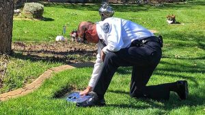 Chad Reyes kneels at Dingo's headstone in the Memorial Mountain View Cemetery