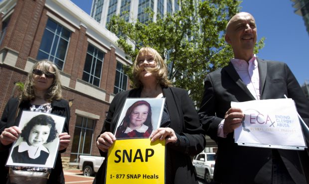 Becky Ianni, center, a victim of priest abuse, holds a picture of her younger self along with other...