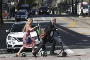 E-scooter renters push with their legs to get the scooter going as they cross Main Street in Salt Lake City on Friday, April 19, 2019. (Photo: Steve Griffin, Deseret News)