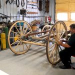 Eli Anderson sands the wheels of his latest project, a carriage used to take tourists around Yellowstone National Park.