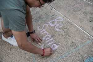 Juan Perez, 17, writes with chalk during a vigil at the University of Texas of the Permian Basin (UTPB) for the victims of a mass shooting, September 1, 2019 in Odessa, Texas. Seven people had been killed, in addition to the gunman and at least 21 others were wounded, including three law enforcement officers after a gunman went on a rampage. The man who has not been identified fled from state troopers who had tried to pull him over. The gunman then hijacked a United States postal van and indiscriminately fired from a rifle at people before the authorities shot and killed him outside a movie theater in Odessa. (Photo by Cengiz Yar/Getty Images)