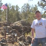 Steve Hunt poses by an American flag, which was set up to honor an aircraft that crashed at the southern Utah site during WWII.