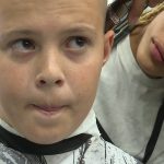 Jayden gets a closer look at the hair of his client, Tevin Day, at American Beauty Academy in West Valley City.