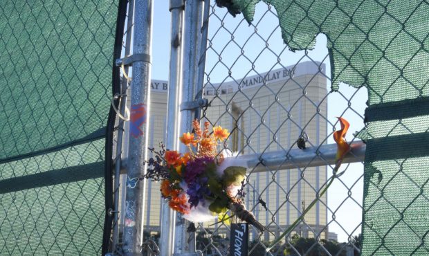 Flowers and a sign reading "HONOR 58" hang on a fence outside the Las Vegas Village across from Man...