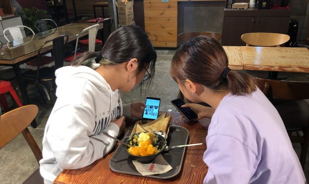 Yoo Chae-rin (left) shows photos of various hairstyles to her friend Kim Hyo-min (right) in a coffe...
