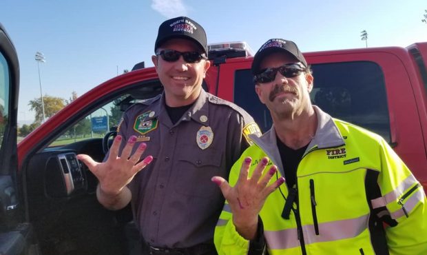 Firefighters show off their new nails after a young girl who was in a crash calmed down while apply...