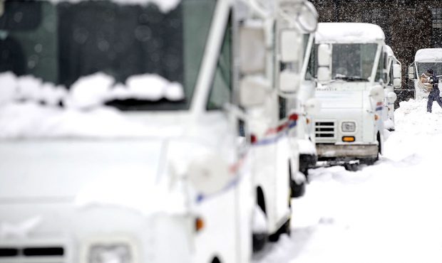FILE: A letter carrier walks through snowdrifts to his mail truck. (Photo by Jeff Zelevansky/Getty ...
