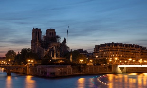 Passenger ferries pass by the Notre-Dame Cathedral after sunset two days after a fire that caused w...