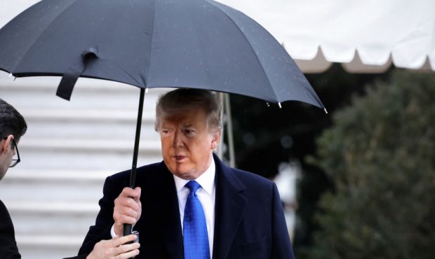 U.S. President Donald Trump takes an umbrella from an aide as he walks out of White House December ...