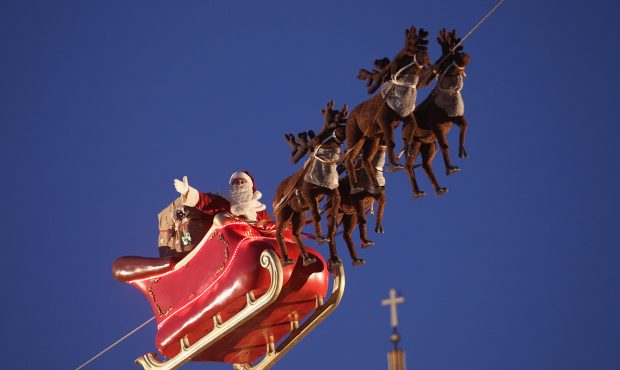 An actor dressed as Santa Claus waves from a suspended sleigh over a Christmas market as the Dom ca...