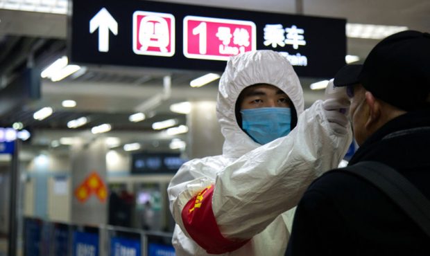 A health worker checks the temperature of a man entering the subway on January 26, 2020 in Beijing,...