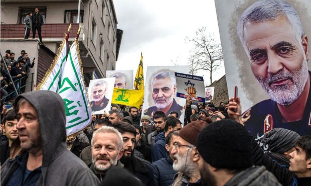 People hold posters showing the portrait of Iranian Revolutionary Guard Major General Qassem Soleim...