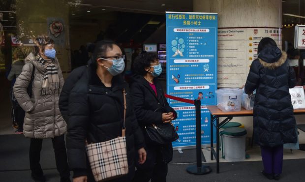 People walk next to signage detailing hygenic practices to prevent the spread of a SARS-like corona...