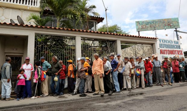 FILE: Men stand in line outside Doris Ortegano's house waiting for what may be their only meal for ...