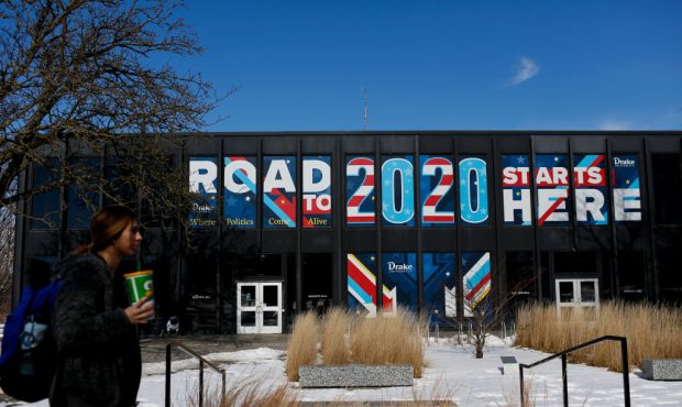 A woman walks past a sign displayed on a building a Drake University that reads "Road To 2020 Start...