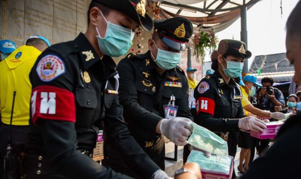 Thai officials administer face-masks at a handout station in the Chatuchak weekend market on Februa...