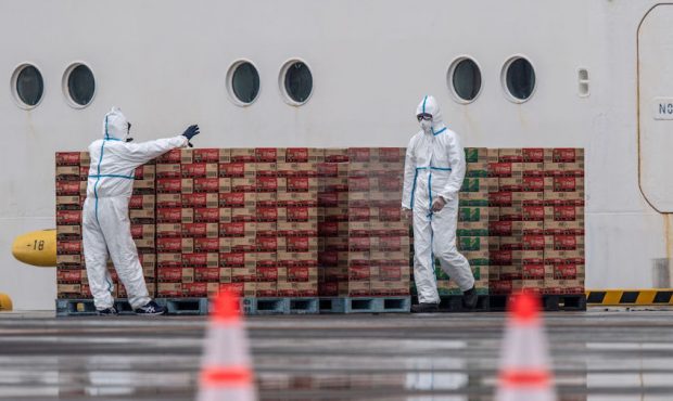 Workers in protective clothing load soft drinks onto the Diamond Princess cruise ship as it sits at...