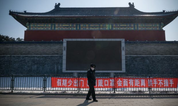 BEIJING, CHINA - FEBRUARY 15: A security guard walks past a propaganda banner saying "Do Not Leave ...
