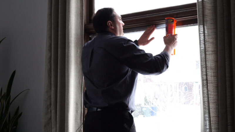 Matt Gephardt applies tape to plastic shrink wrap over a hundred-plus-year-old window. (KSL TV) 