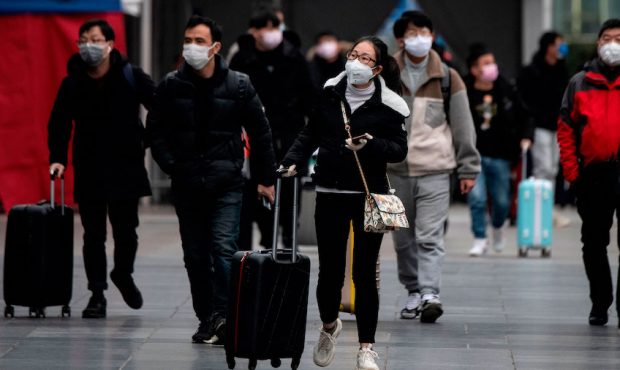 People wearing protective face masks arrive at a railway station in Shanghai on February 10, 2020. ...