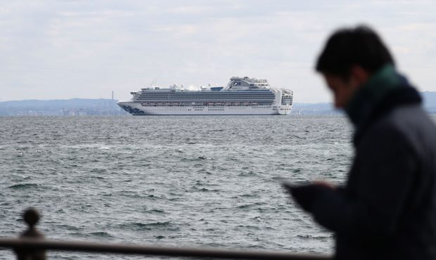 A member of the media checks his phone as the Diamond Princess cruise ship with over 3,000 people s...
