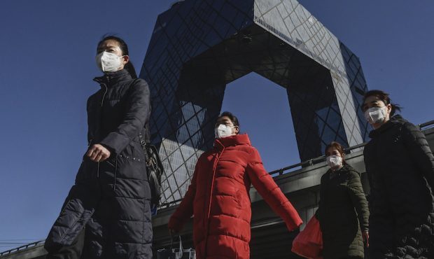 Chinese women wear protective masks as they pass the CCTV building on their way to work on February...
