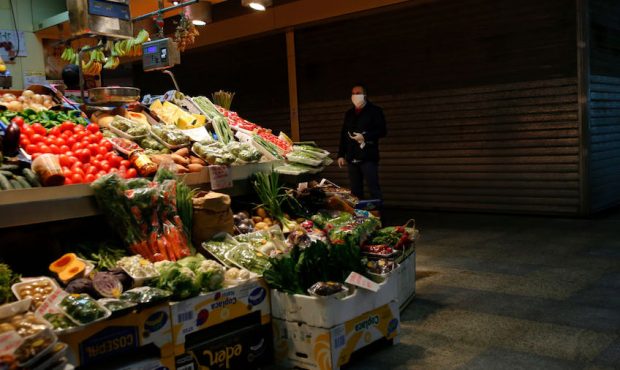 A man wearing a protective mask buys groceries in an empty market on April 06, 2020 in Seville, Spa...