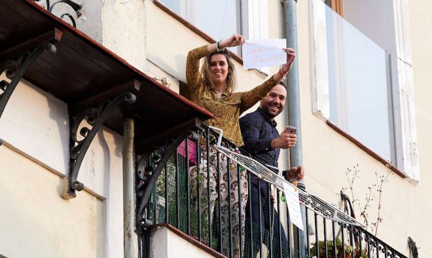 Two people look out from their balcony showing a banner which reads ''Many thanks neighbors'' on Ap...