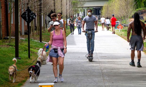 Marcus Bouliany, center, wears a mask while making his way along the BeltLine in Atlanta, during th...