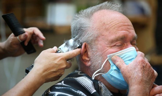 Lonnie Sullivan covers his face with a mask while getting a haircut at The Barber Shop in Broken Ar...