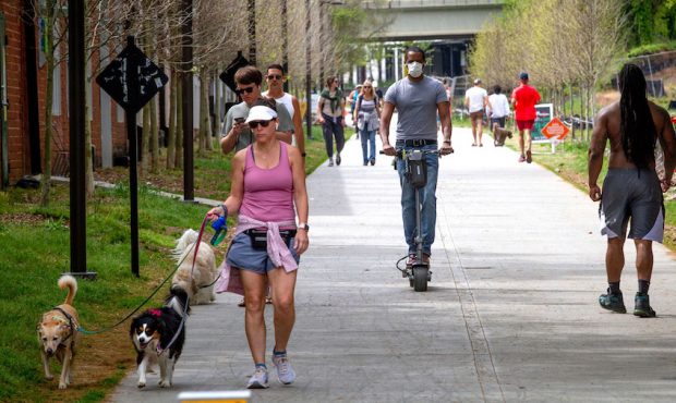 Marcus Bouliany, center, wears a mask while making his way along the BeltLine in Atlanta, during th...