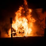 MINNEAPOLIS, MN - MAY 27: A car burns near the Third Police Precinct on May 27, 2020 in Minneapolis, Minnesota. A number of businesses and homes were damaged as the area has become the site of an ongoing protest after the police killing of George Floyd. Four Minneapolis police officers have been fired after a video taken by a bystander was posted on social media showing Floyd's neck being pinned to the ground by an officer as he repeatedly said, "I can’t breathe". Floyd was later pronounced dead while in police custody after being transported to Hennepin County Medical Center. (Photo by Stephen Maturen/Getty Images)