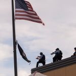 MINNEAPOLIS, MN - MAY 27: Police officers stand on the roof of the Third Police Precinct with weapons aimed at protesters below on May 27, 2020 in Minneapolis, Minnesota. The station has become the site of an ongoing protest after the police killing of George Floyd. Four Minneapolis police officers have been fired after a video taken by a bystander was posted on social media showing Floyd's neck being pinned to the ground by an officer as he repeatedly said, "I can’t breathe". Floyd was later pronounced dead while in police custody after being transported to Hennepin County Medical Center.  (Photo by Stephen Maturen/Getty Images)