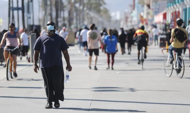 A man wears a face mask along a boardwalk on the day Los Angeles County reopened its beaches, which...