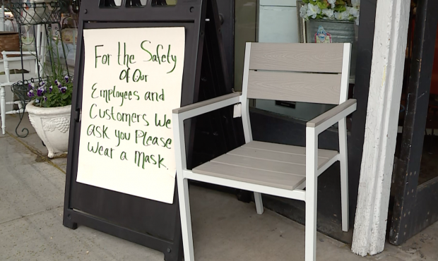 A sign outside a consignment shop in Salt Lake City asks customers to wear masks while inside....