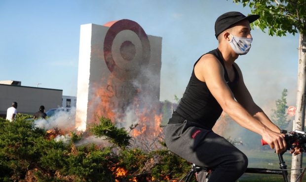A cyclist rides past a fire outside of a Target store which was set during a protest on May 28, 202...