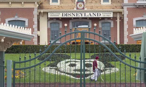 An employee cleans the grounds behind the closed gates of Disneyland Park on the first day of the c...