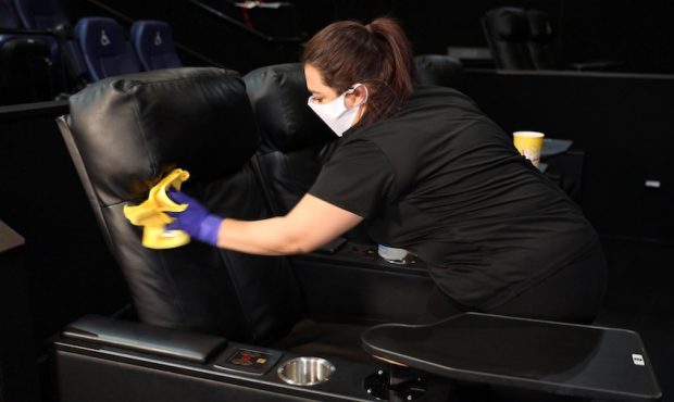 An employee cleans a chair at a Megaplex Theatres location as the chain prepares to reopen its door...