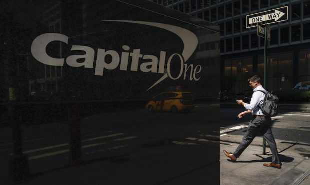 A man checks his phone as he walks past the Capital One offices in Midtown Manhattan on July 30, 20...