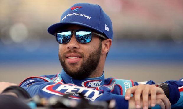 Bubba Wallace, driver of the #43 Victory Junction Chevrolet, stands by his car before qualifying fo...