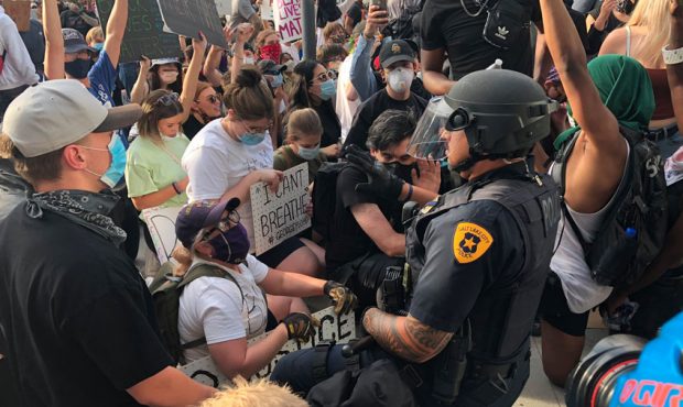 An officer with the Salt Lake City Police Department takes a knee with demonstrators durinig a peac...