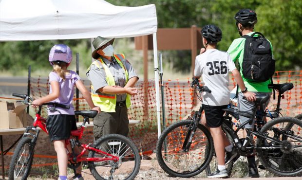Bike riders get information from a masked ranger at Zion National Park on May 15, 2020 in Springdal...