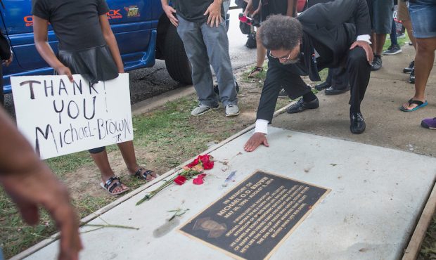 FILE: Activist Cornel West pauses to clear debris from a plaque in the sidewalk which honors Michae...